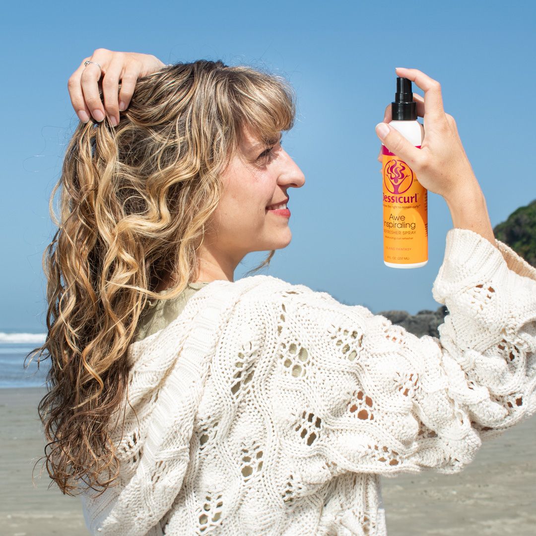 wavy haired girl at the beach refreshing her waves with Jessicurl Awe Inspiraling Spray