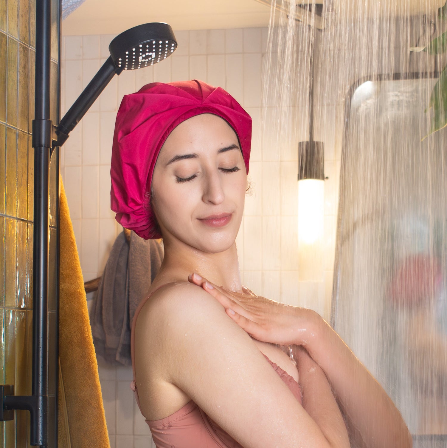 relaxed curly haired woman in the shower with her hair in a shower cap