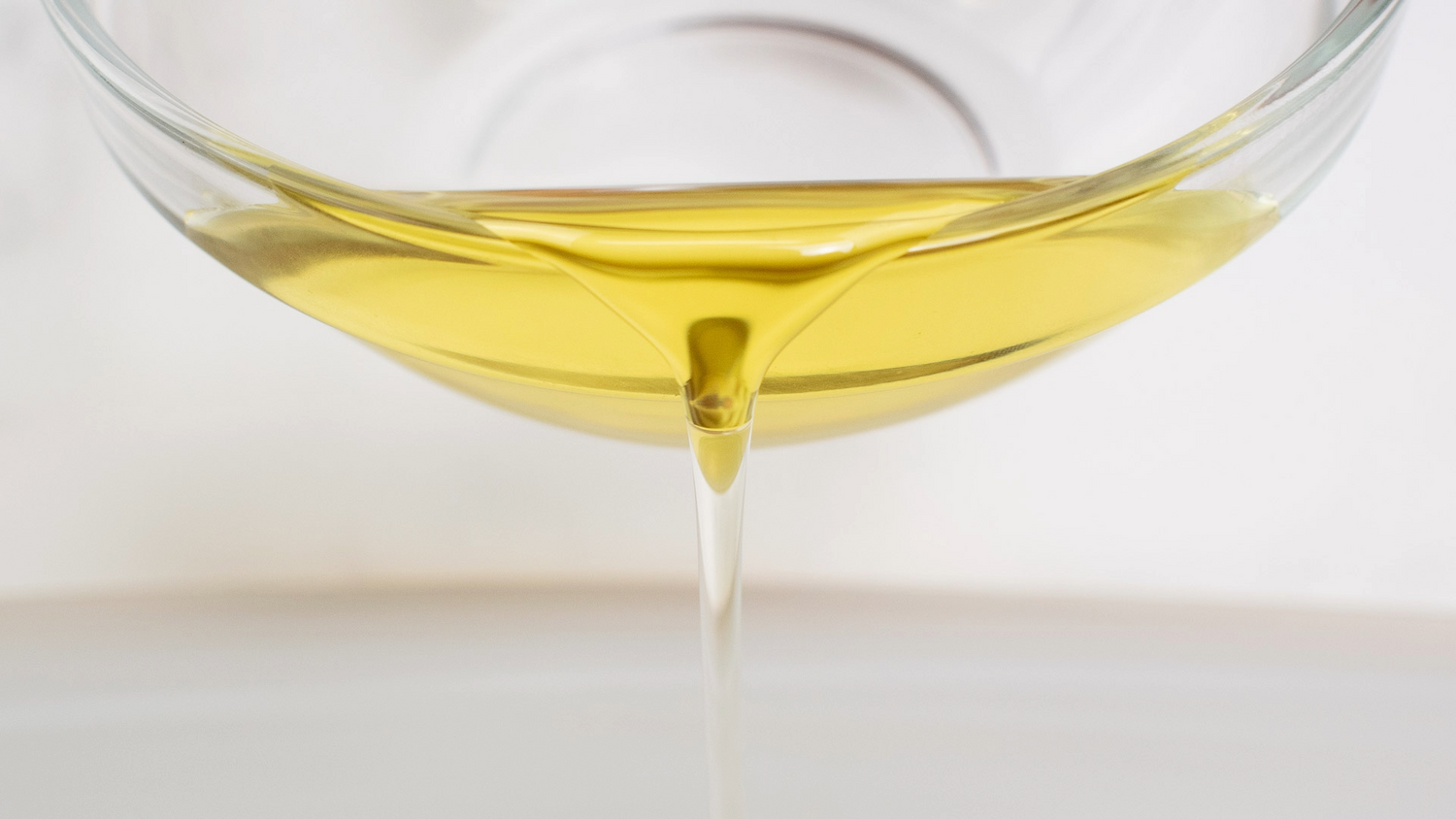 avocado oil in a small glass being poured in front of the camera