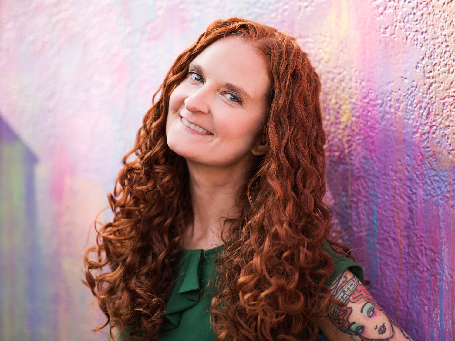 Founder Jessica McGuinty smiling leaning up against a painted wall