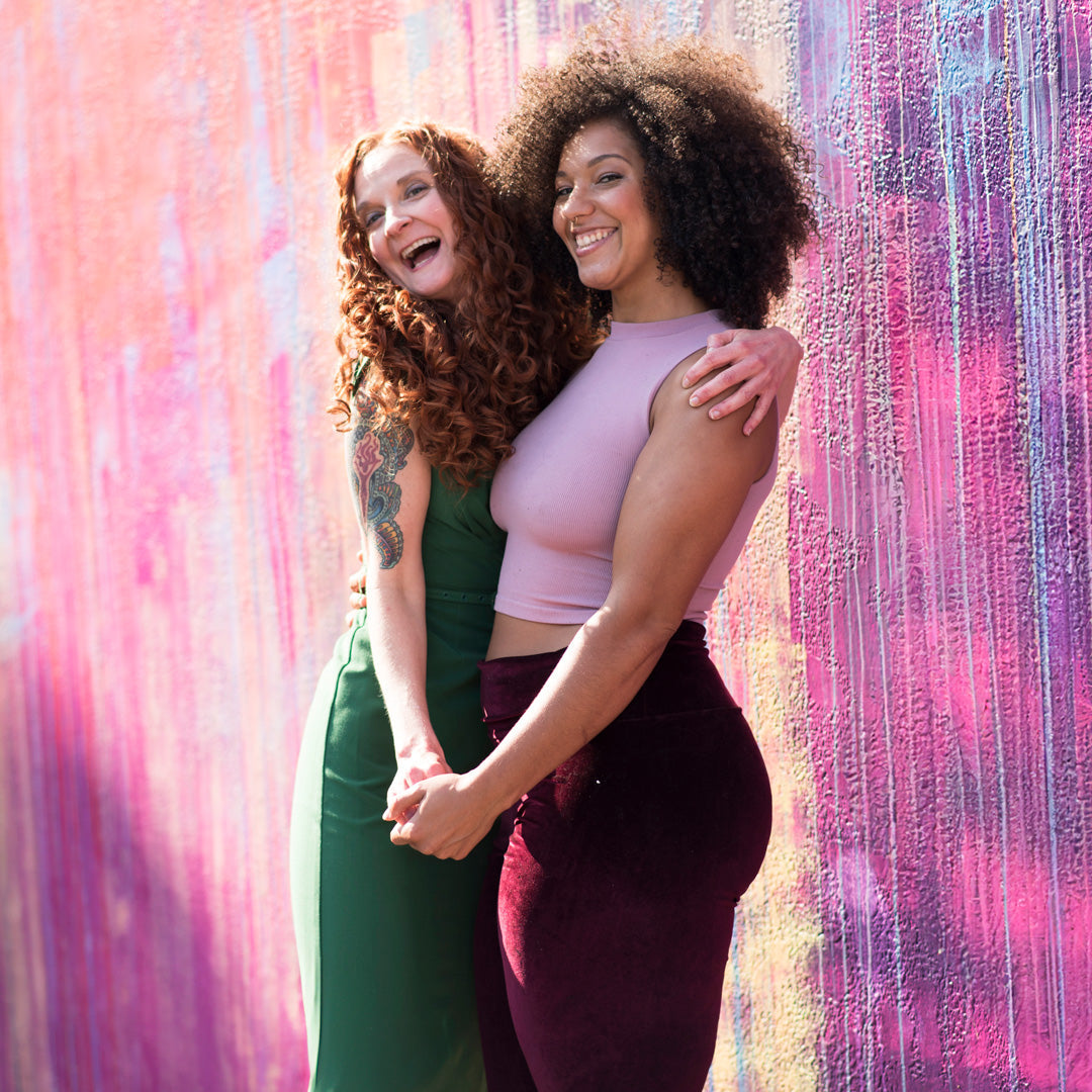Jessica McGuinty with fellow curly smiling together against a painted wall